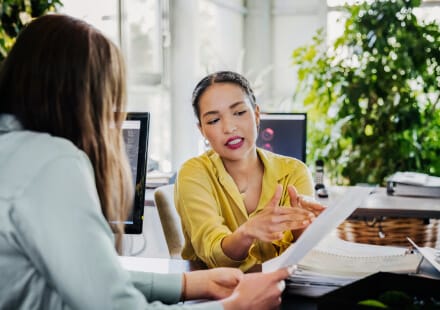 Two women reviewing paperwork in sunny office