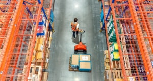 Man operating motorized dolly to gather items in warehouse