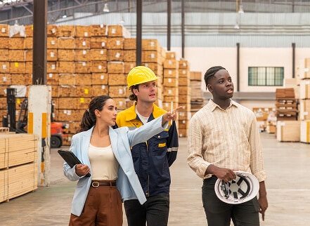 Two workers with hard hats and their supervisor having a conversation about work going on in the distance.