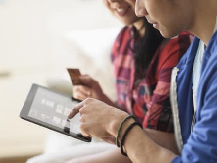 Two people with a credit card and a tablet
