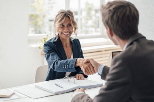 Smiling woman and man shaking hands across a desk