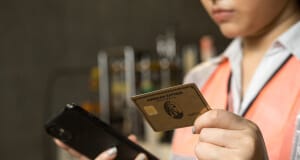 Woman holding American Express gold card and smartphone