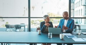 Man and woman conversing while looking at a laptop