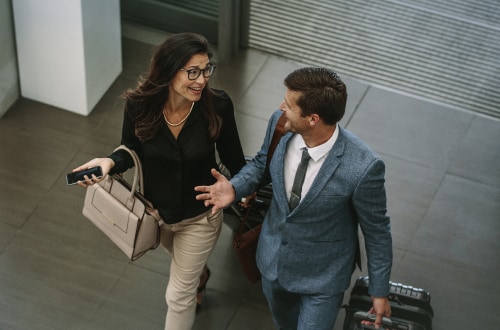 Man and woman walking through hall engaged in conversation