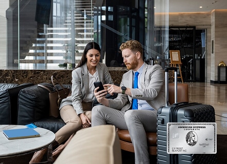 Man and woman sitting in lounge with suitcases looking at phone