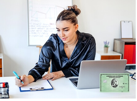 Woman sitting at desk with laptop writing in notepad