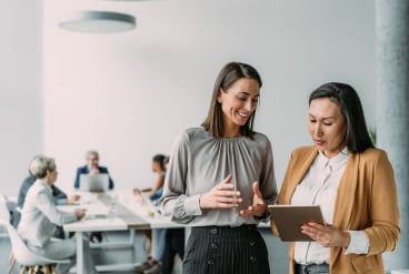 Two women talking in conference room.
