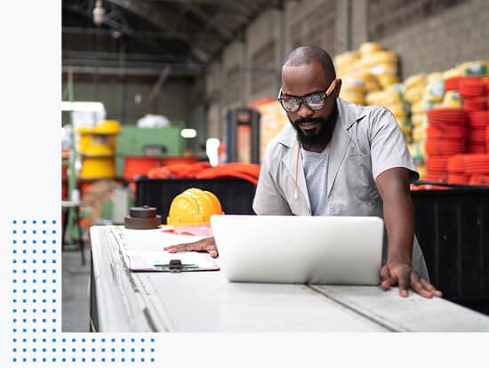  Man in construction warehouse standing at table and looking at laptop