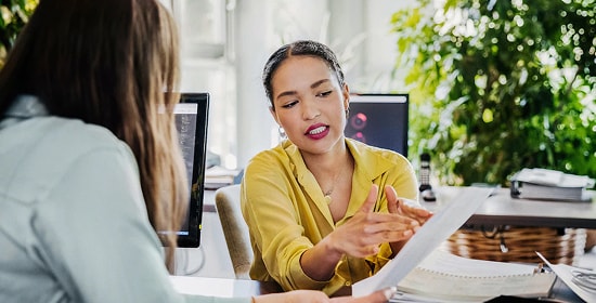  Woman in her office working with a coworker and looking at documents
