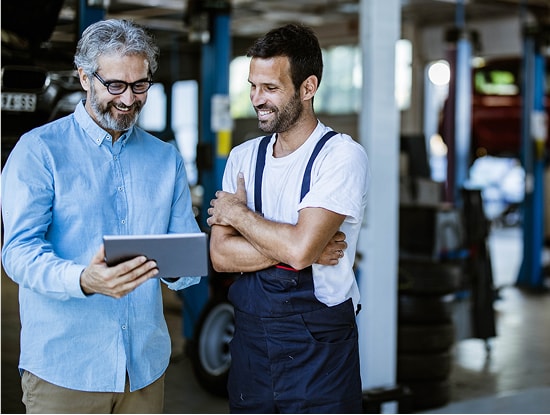 Two men in a workshop looking at a tablet device