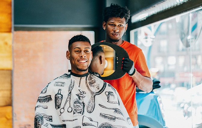 Barber showing customer the back of hair using mirror