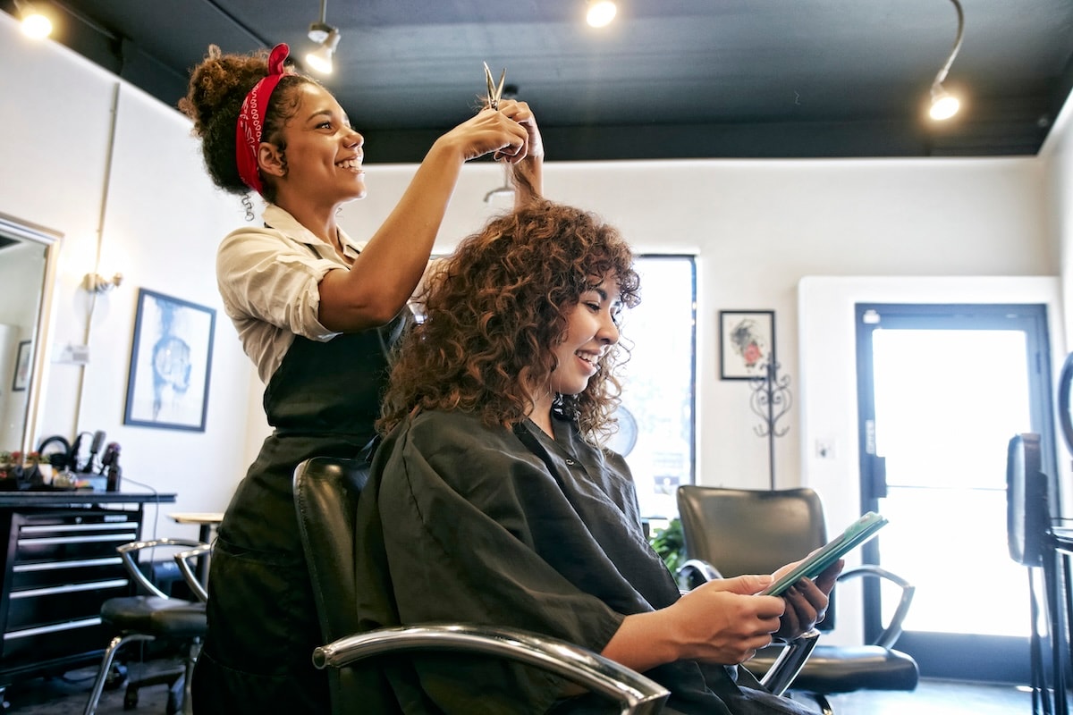 Hairdresser cutting a client's hair who is sitting in a salon chair
