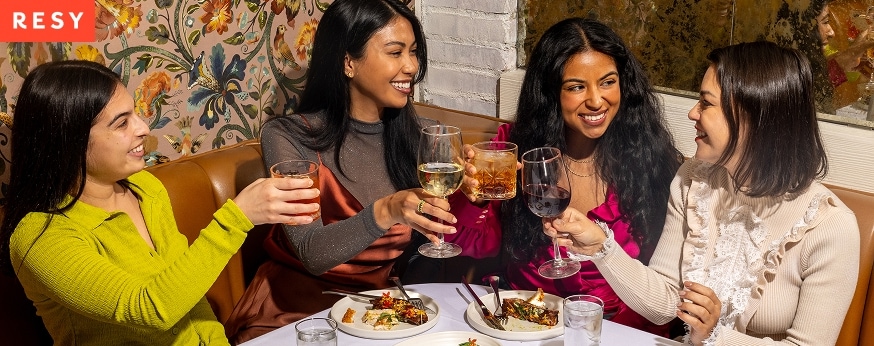Group of women toasting at a restaurant corner booth