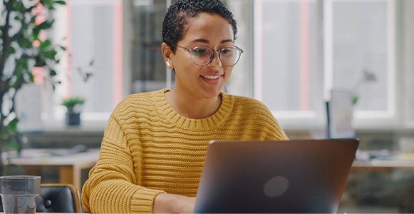 Woman typing on laptop in open workspace.
