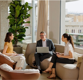 Three colleagues speaking together in a lounge.