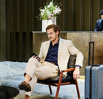 Businessman sitting in hotel lounge with suitcase.