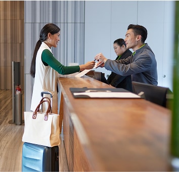 Woman at airport service desk with her carry-on luggage.