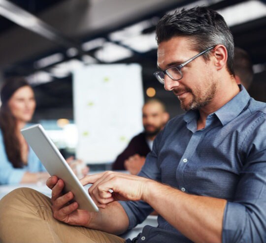 Three people smiling and looking at a laptop.