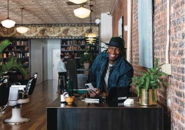 A barber shop owner standing behind the service counter.