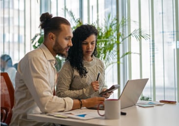 Two colleagues reviewing data while sitting at an office table.