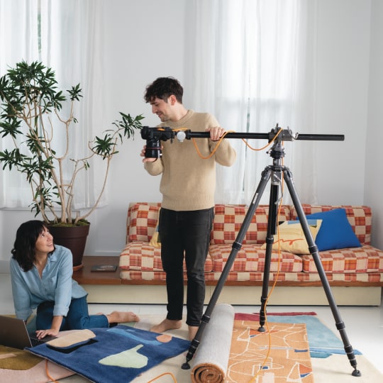 Two colleagues setting up a photoshoot of decorative rugs.