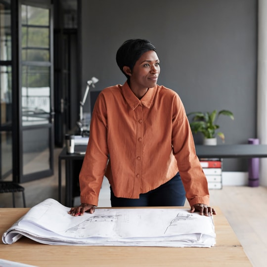 An architect with a stack of blueprints on a table.