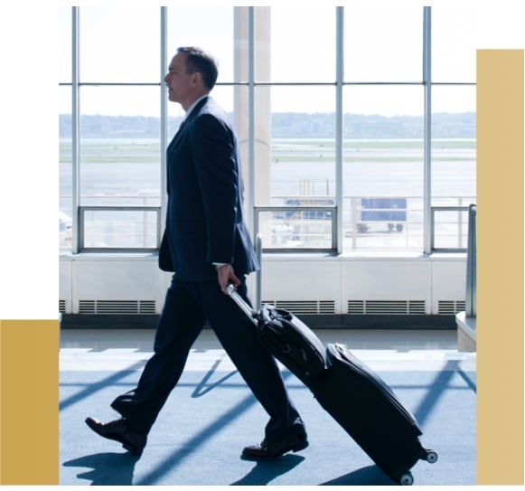 Man in suit walking through airport with luggage.