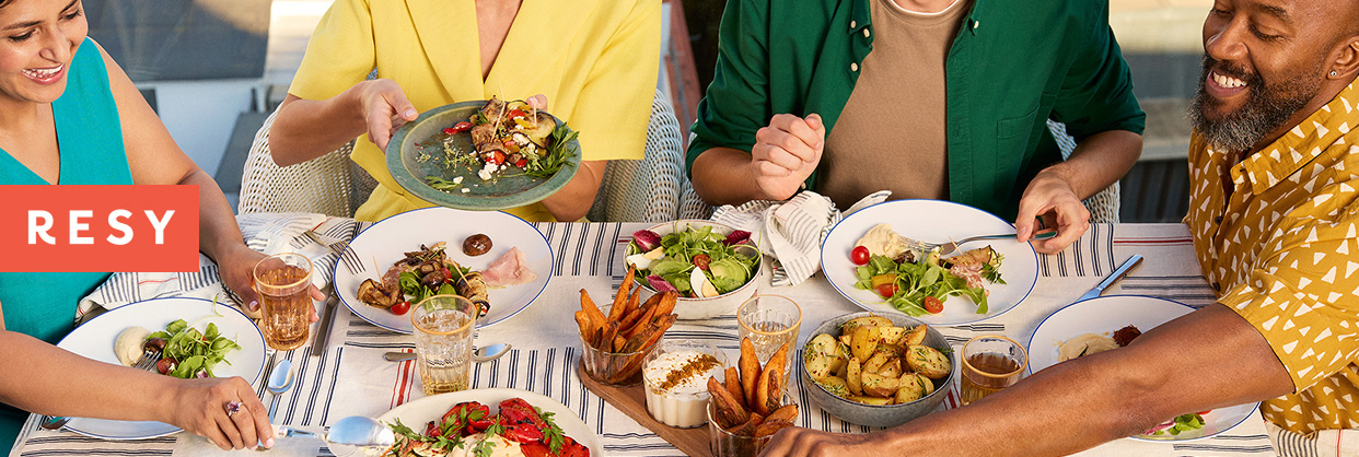 The Resy logo superimposed on a photo of a group dining outdoors.