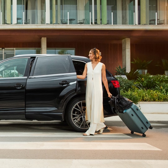 Woman loading luggage into SUV.