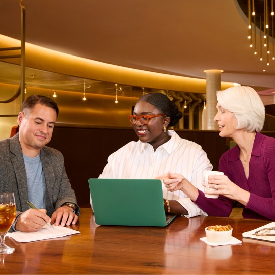 Three colleagues collaborating while sitting in airport lounge.