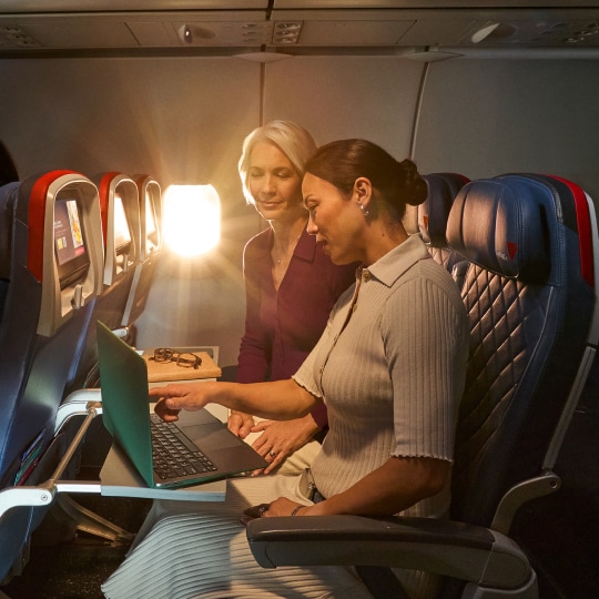 Two colleagues on a laptop while sitting on a Delta flight.