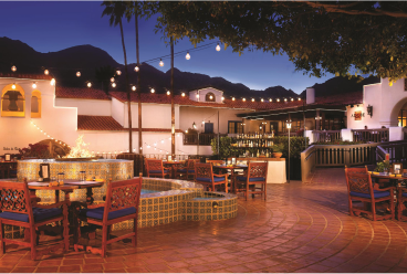 A patio with tables and chairs, bathed in the soft glow of dusk.