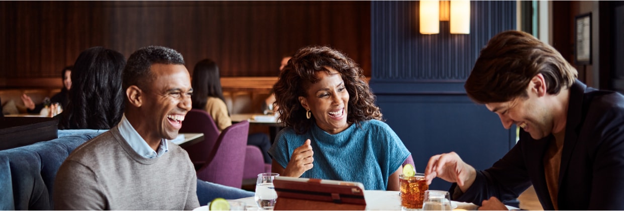 A man sitting in lounge chair looking at a tablet.