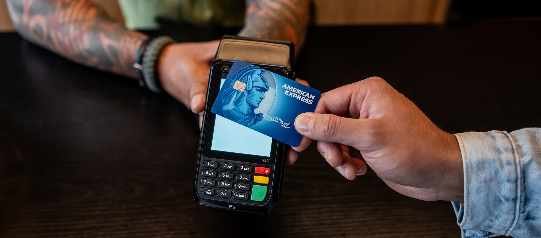 Woman looking at a laptop with a baby that's holding a phone sitting on her lap