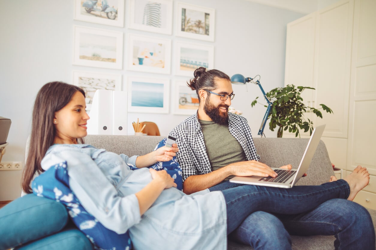 Man and woman on couch with laptop and credit card