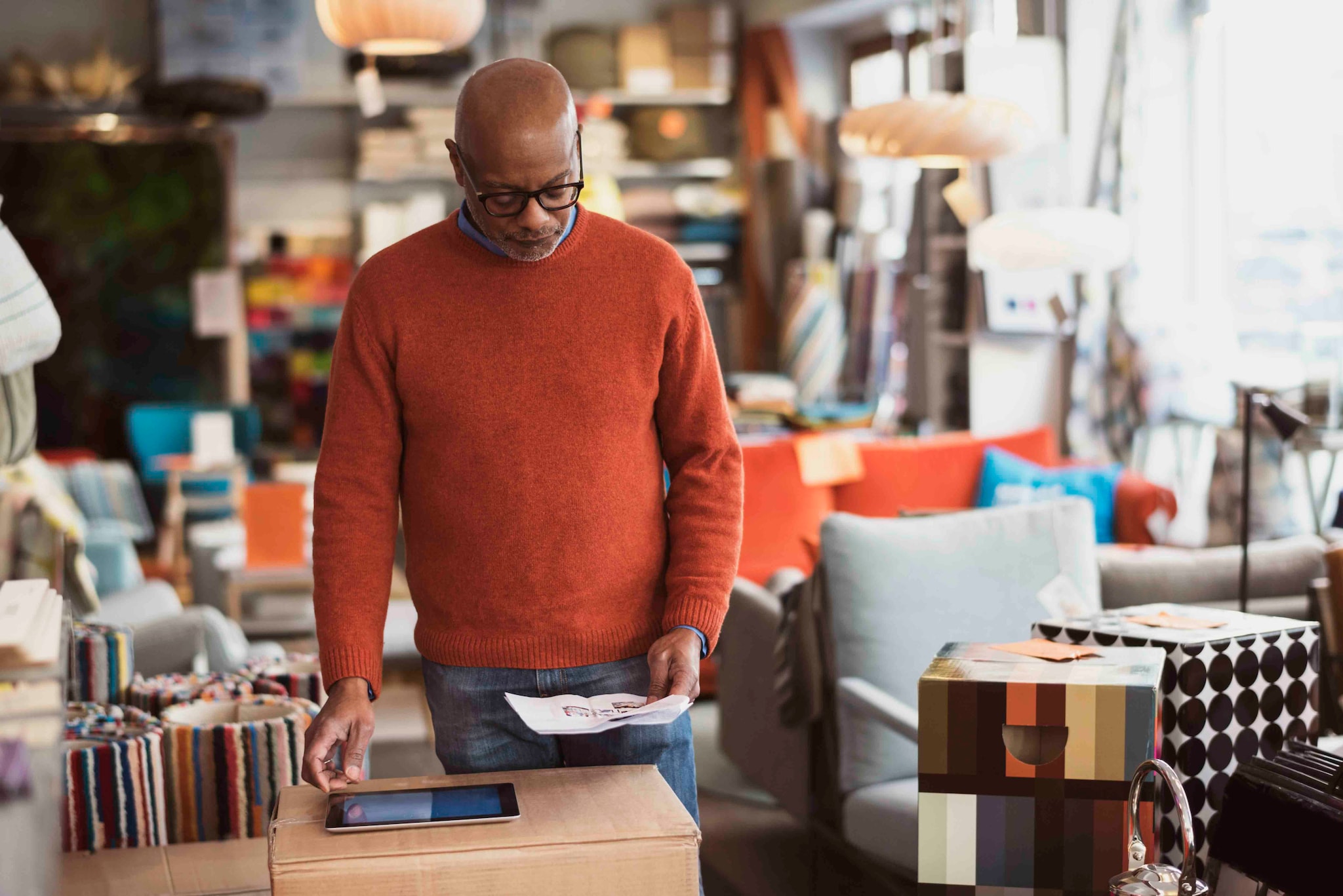 Man is in the department store, looking at the image and searching something on the tablet