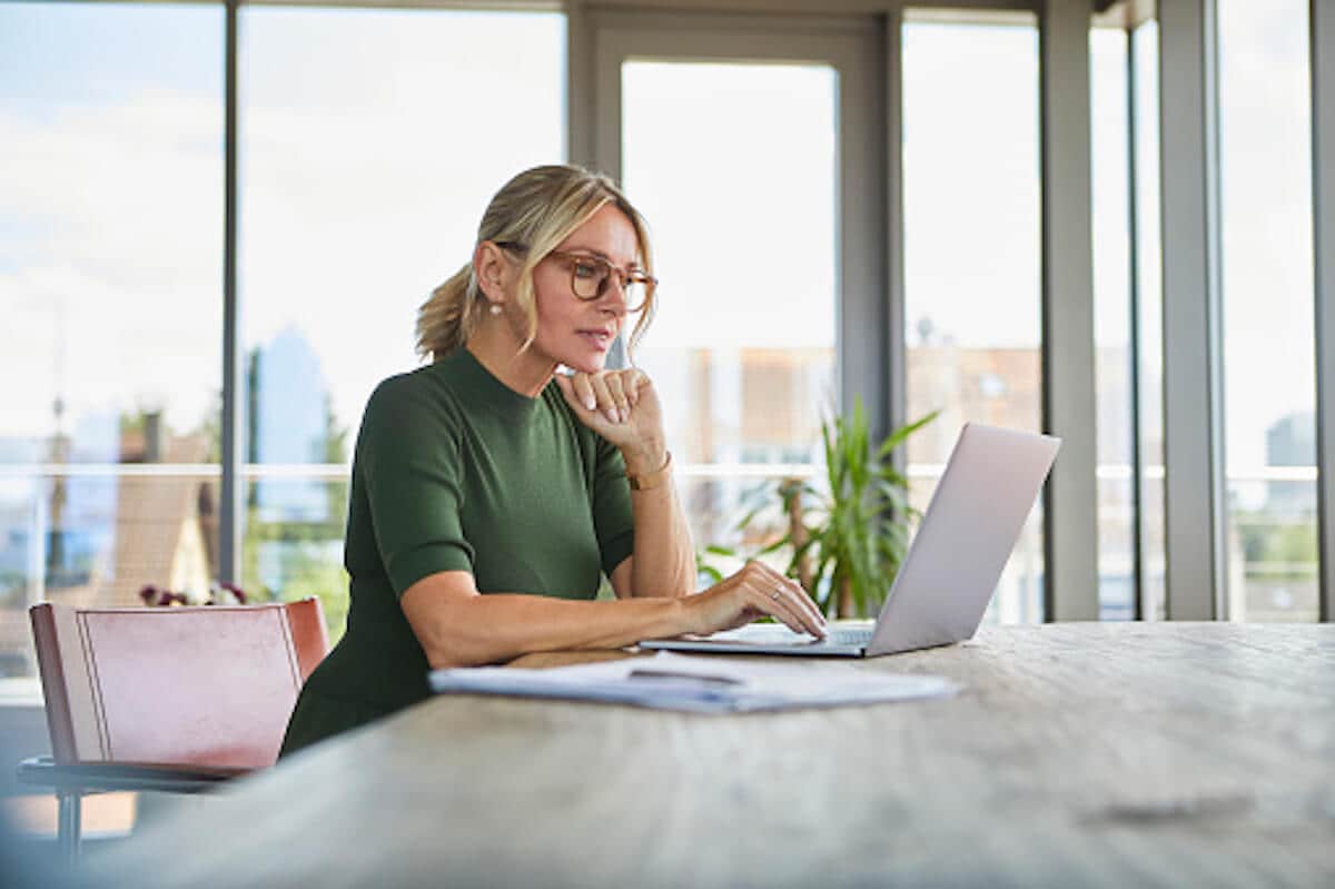 Woman is in the office with the city view, using the laptop