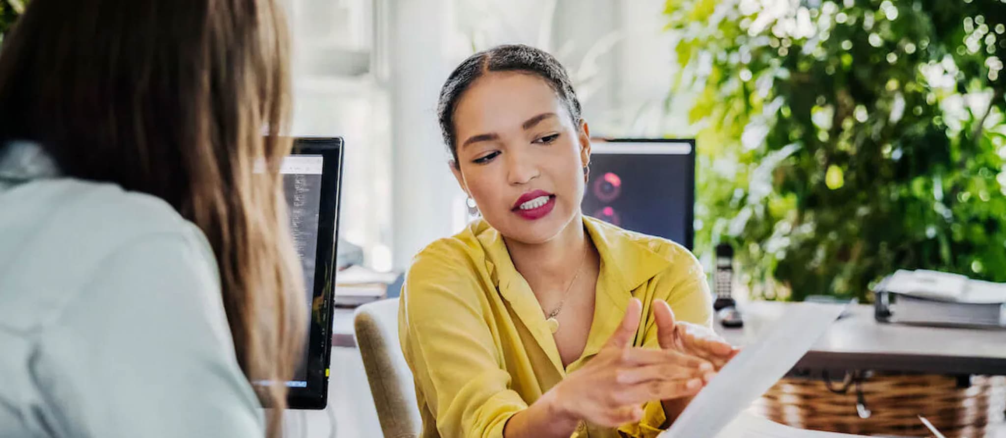 Two women are talking in the office and looking through paperwork