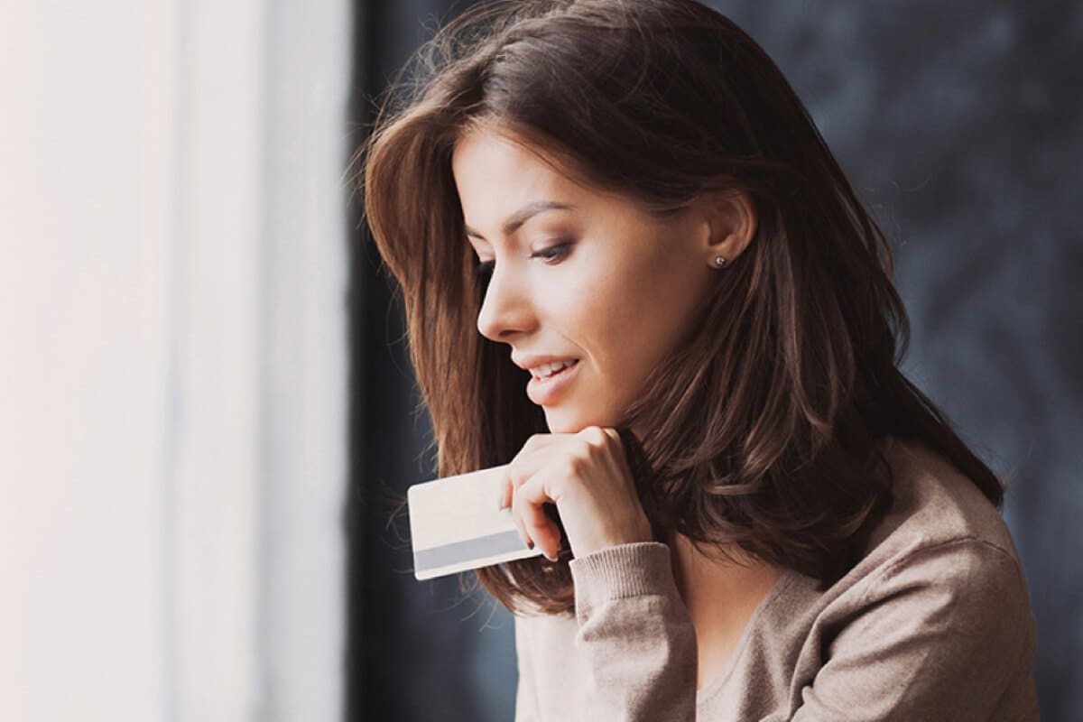 Woman is using a laptop and holding a credit card in coffee shop