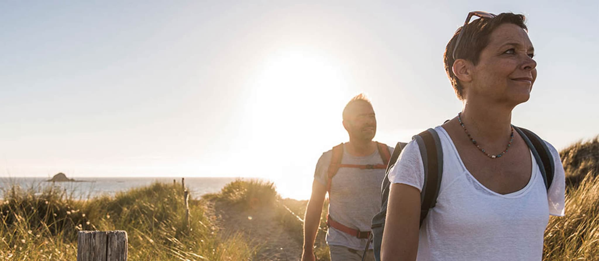 A man and woman enjoy a coastal walk, contemplating their journey and the advantages of a Roth Individual Retirement Account.
