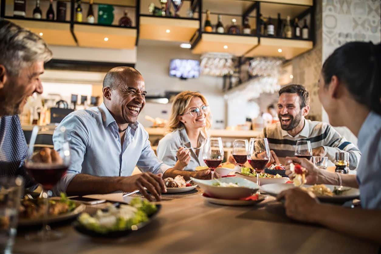 group of friends laughing and eating at a restaurant