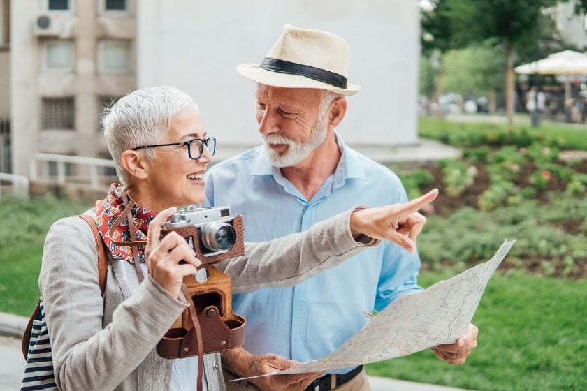 Older couple holding a map and camera outside