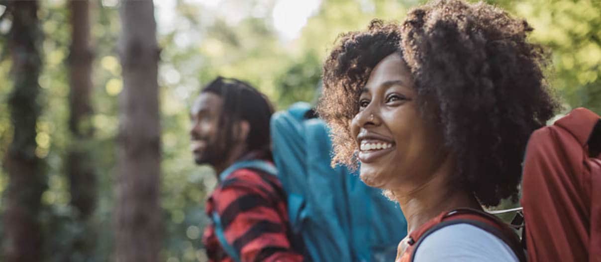 Man and woman smiling while hiking in the woods