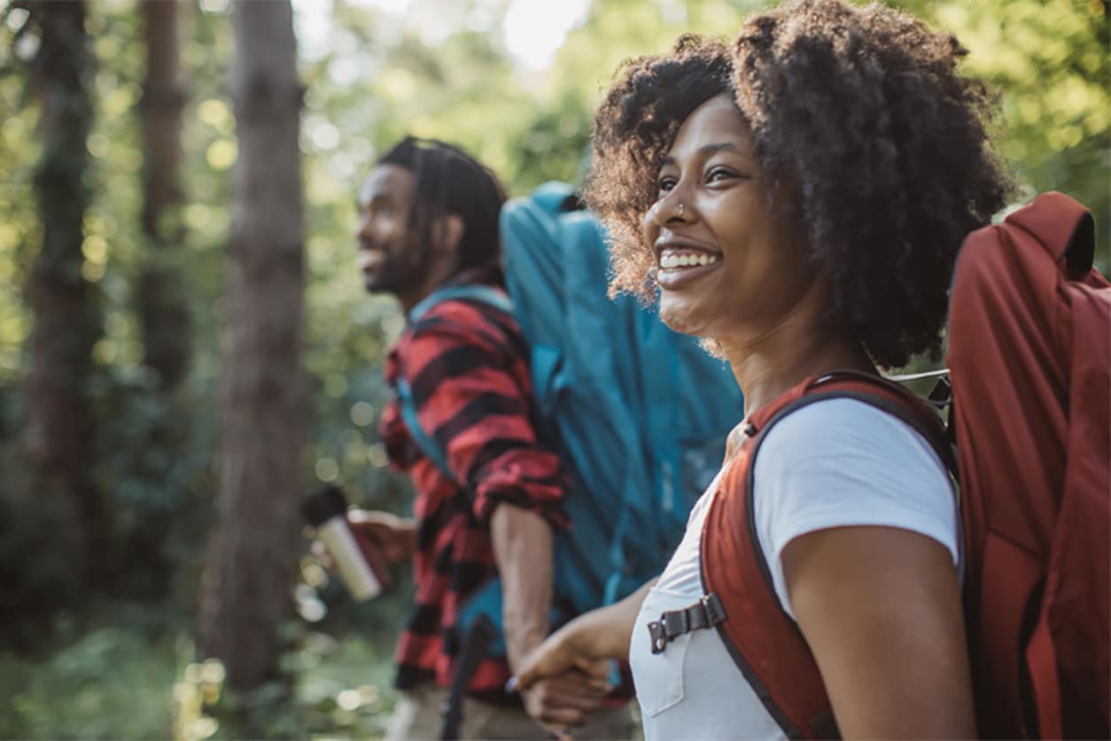 Man and woman smiling while hiking in the woods
