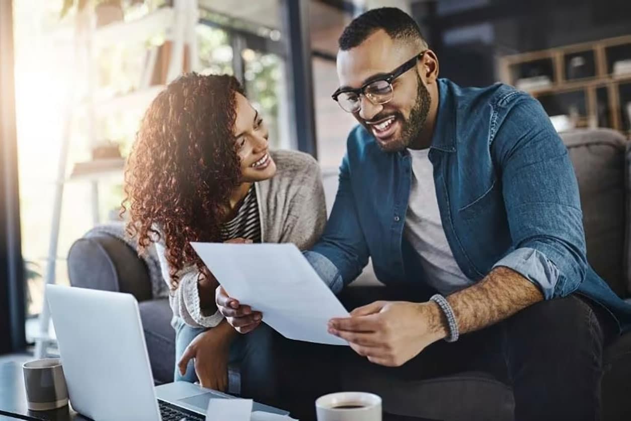 Woman and man are sitting in a room smiling and looking at a document