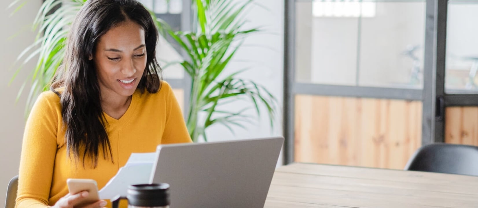 A person holding a bill and doing research on smartphone.