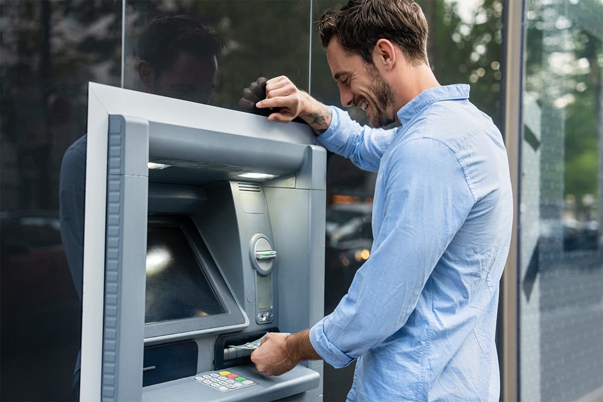 Someone inserting cash into an ATM.