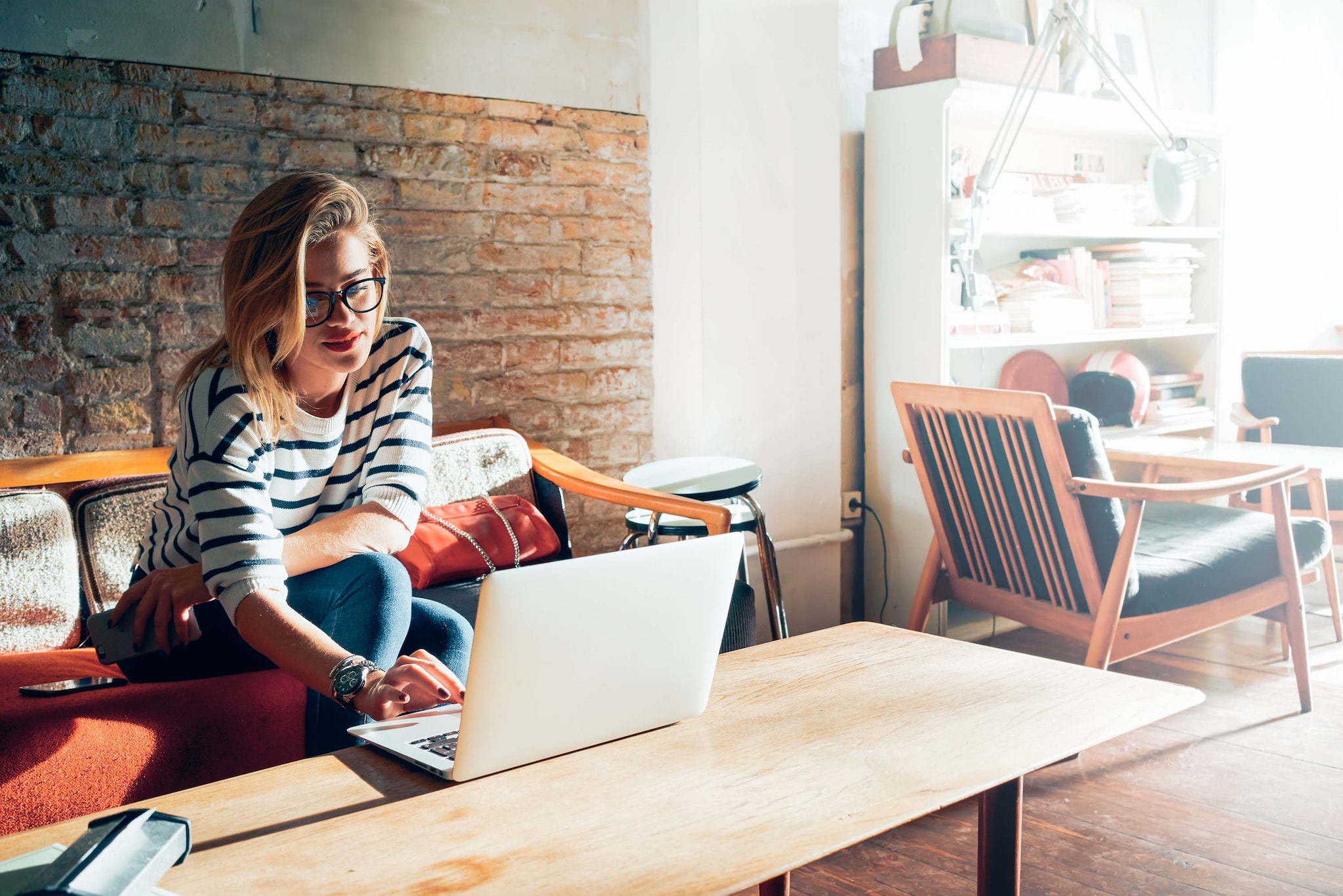 While sitting on her living couch a woman checks her loan status via her laptop.
