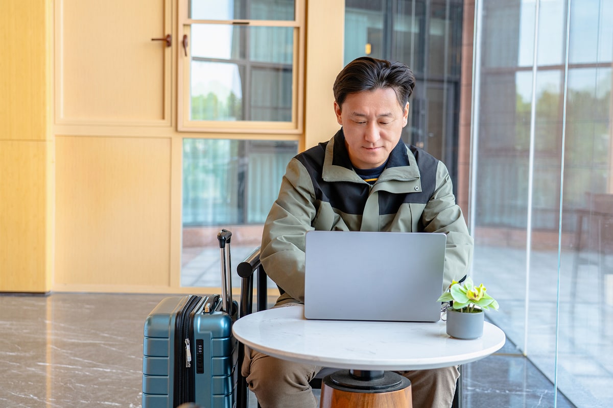 A professional image of a traveler reviewing travel insurance options on a laptop, with a suitcase and passport nearby.