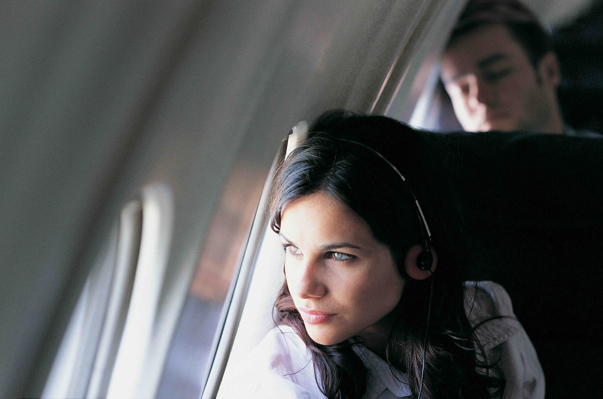 A woman wearing headphones sits comfortably in an airplane, ready to enjoy her journey with cash back or travel rewards.